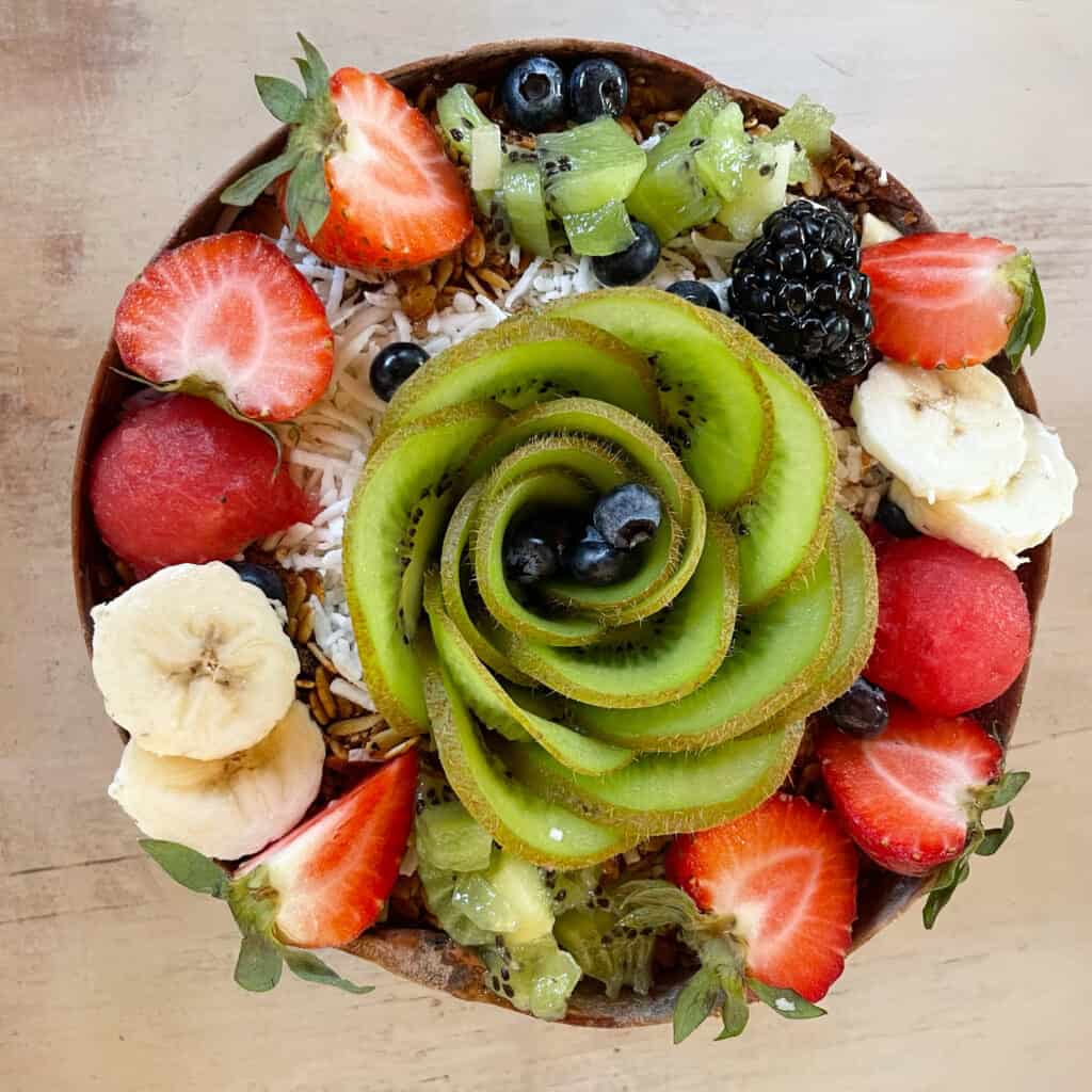 Smoothie bowl topped with kiwi, strawberry, banana, blueberries.
