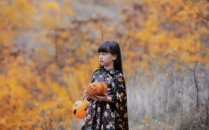 Child in costume holding two pumpkins
