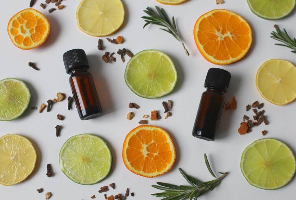 Essential oils on a plate of spices and orange and lime slices.