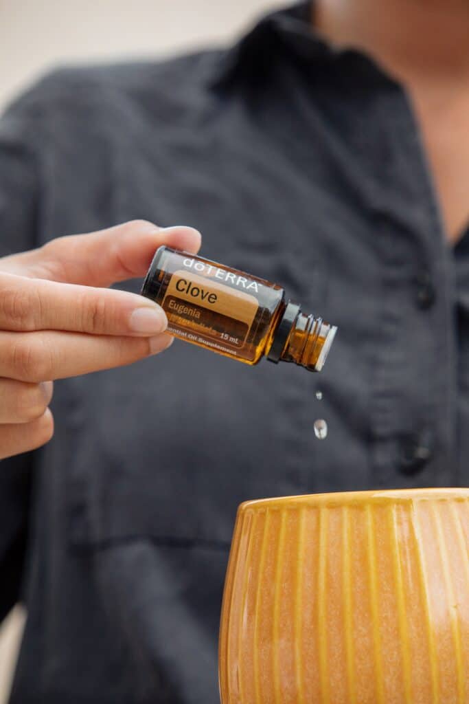 Clove essential oil being poured into a diffuser.