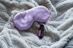 Lavender essential oil on a blanket next to a sleep mask.