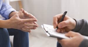 Psychologist listening to his patient and writing notes, mental health and counseling concept, panorama, copy space