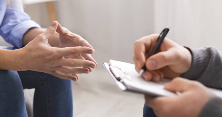 Psychologist listening to his patient and writing notes, mental health and counseling concept, panorama, copy space