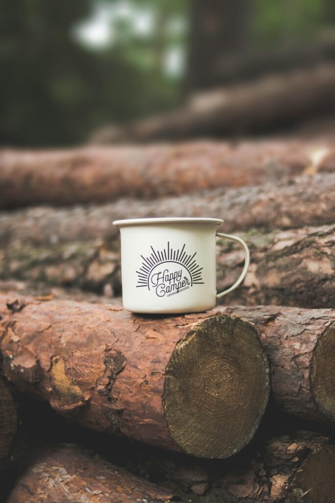 Camping coffee mug on a log.
