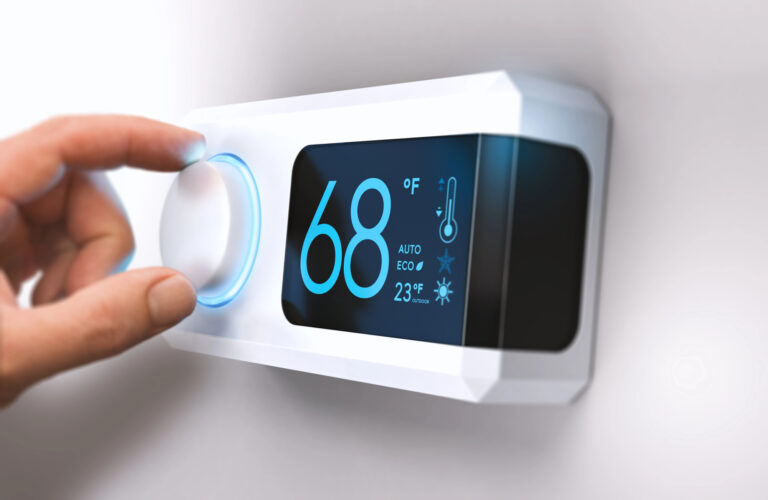 A person's hand is touching the digital thermosta on the wall.