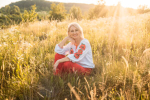 Older woman crouching in a field in the sun.