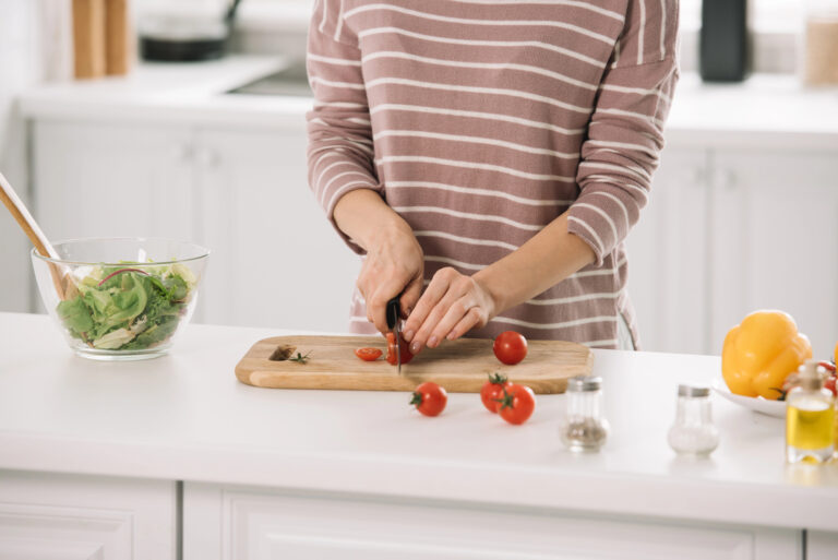 Woman cutting up vegetables on a cutting board.