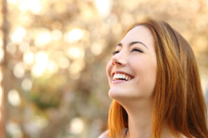 Young woman smiling upwards in the sunshine.
