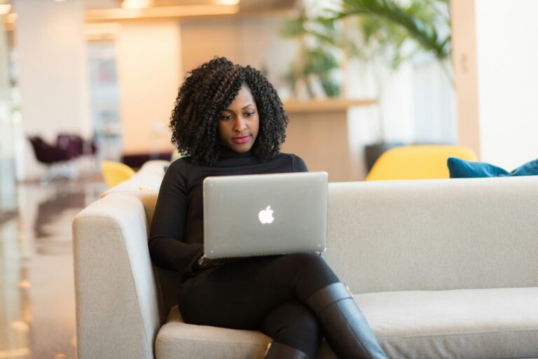 Woman typing on her laptop on a couch.