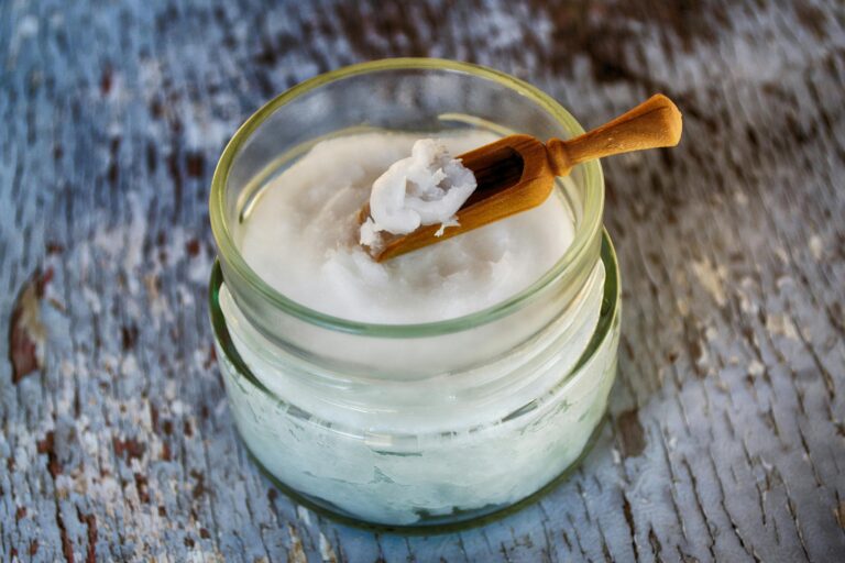 Homemade sugar scrub in a small glass jar with a scoop.