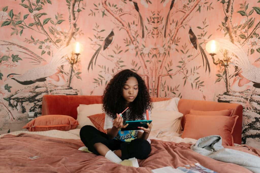 Young girl using a digital device on her bed.